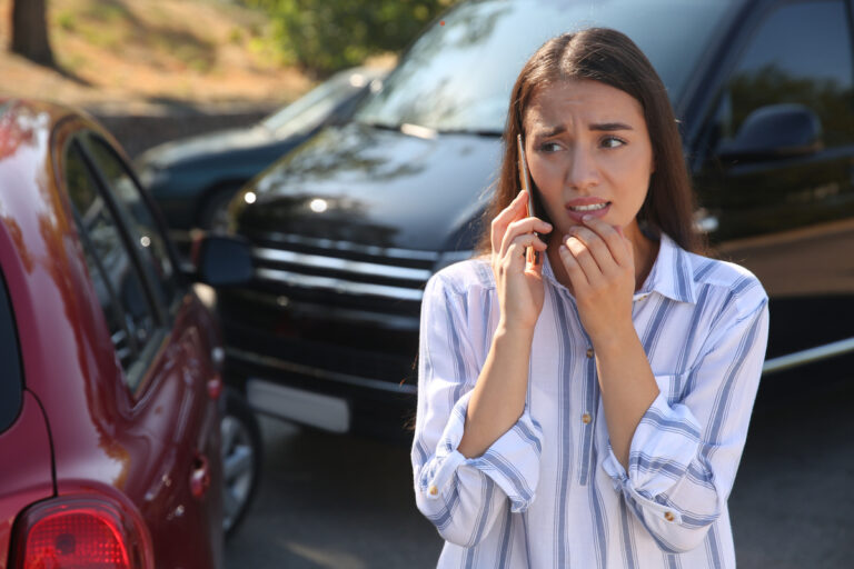 Stressed woman talking on phone after car accident outdoors